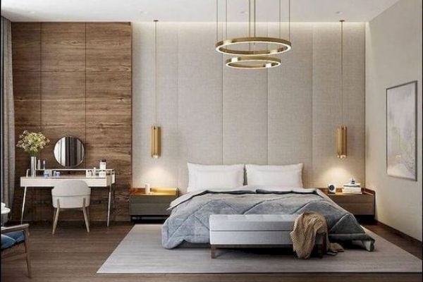 A modern bedroom with a large bed, pendant lights, a dressing table, and a circular mirror, featuring wood accents and stylish décor.