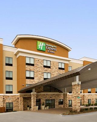 The image shows a Holiday Inn Express & Suites hotel with a large arched entrance and a multi-story building facade.