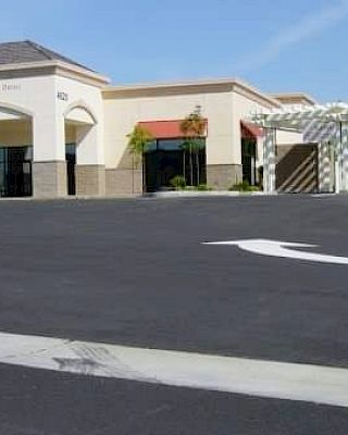 The image shows a bank building with a drive-through lane and an empty parking area under a clear blue sky.