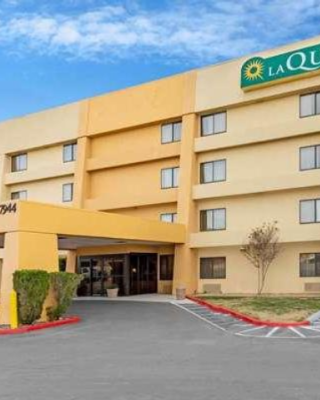 The image shows the exterior of a La Quinta Inn & Suites hotel, featuring a yellow building with a signage and entrance area.