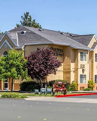 The image shows a yellow two-story hotel building with a sign that reads 