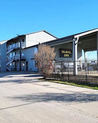 The image shows a three-story motel building with a sign that reads 