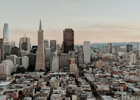 Aerial view of a city skyline with tall buildings and a mix of modern and older architecture at dusk.